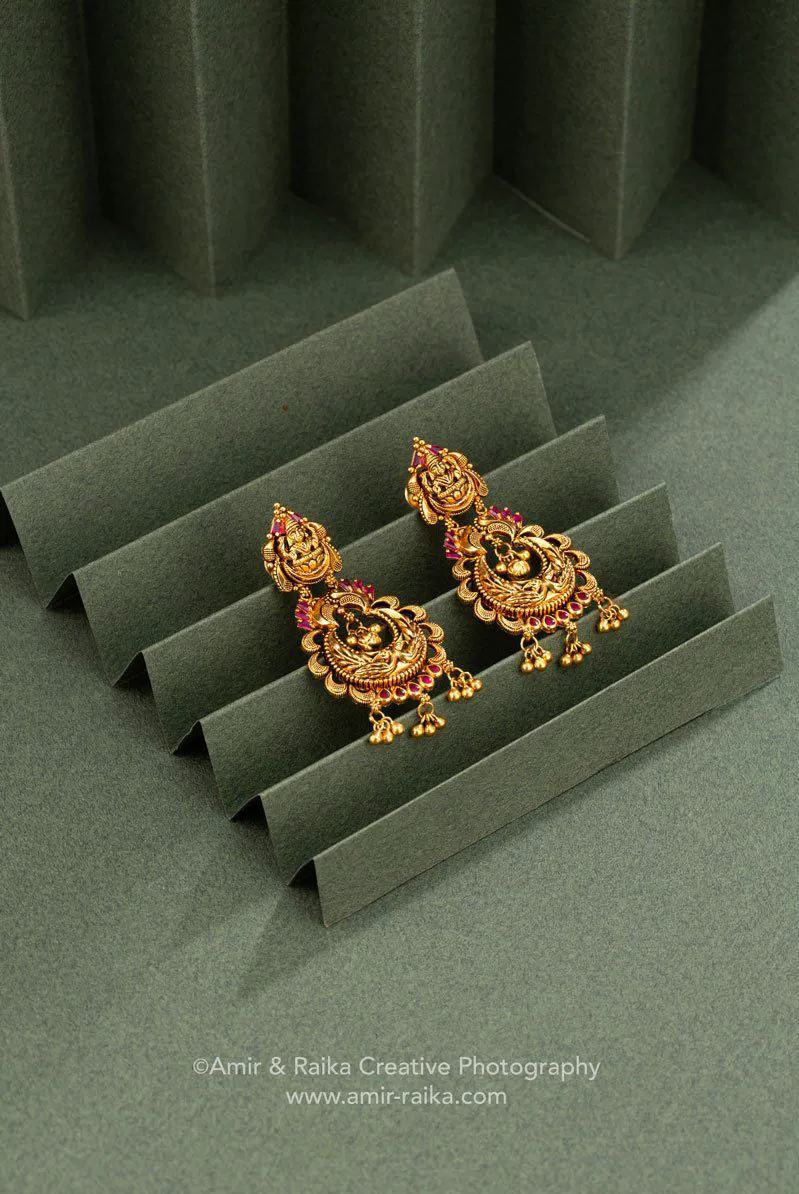 Traditional gold earrings arranged on a sculptural green background